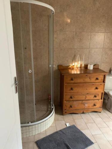 a bathroom with a shower and a wooden dresser at 20 On Plover - Private Cottage in Sandton