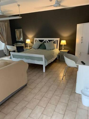 a bedroom with a bed and a couch and chairs at 20 On Plover - Private Cottage in Sandton