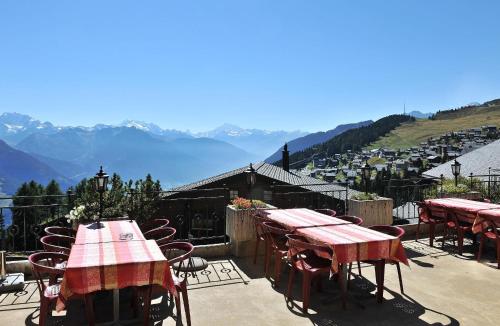 a patio with tables and chairs with mountains in the background at Hotel Aletsch in Bettmeralp