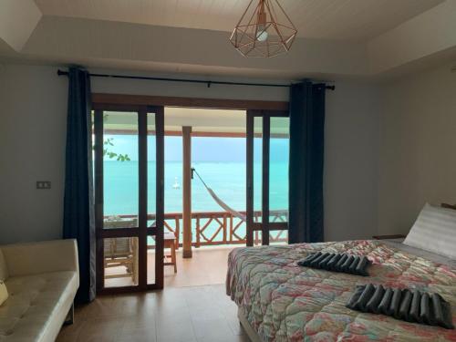 a bedroom with a bed and a view of the ocean at Suncliff Resort in Haad Rin