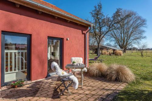 a red house with a table and a chair outside at HofGut Bockelkathen Apartment 7 in Lüdersburg