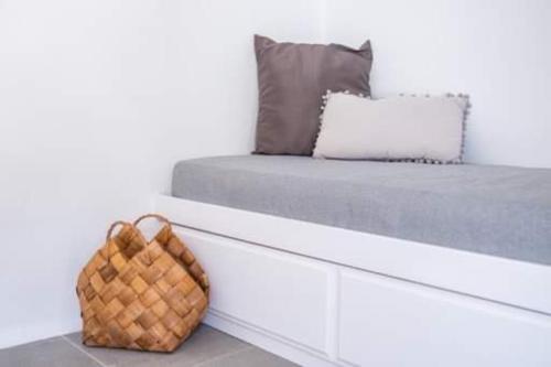 a white bed with a basket sitting on top of it at Grannys Villas finiki in Karpathos Town