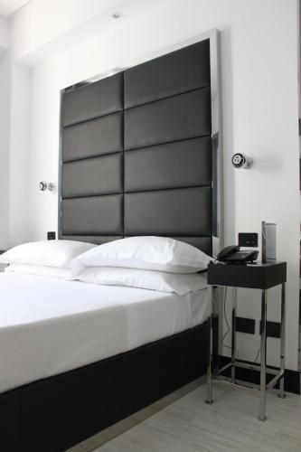 a bed with a black headboard next to a desk at LHP Hotel Napoleon in Milan