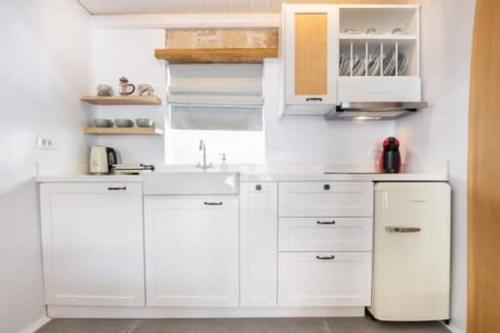 a white kitchen with white cabinets and a sink at Grannys Villas finiki in Karpathos Town