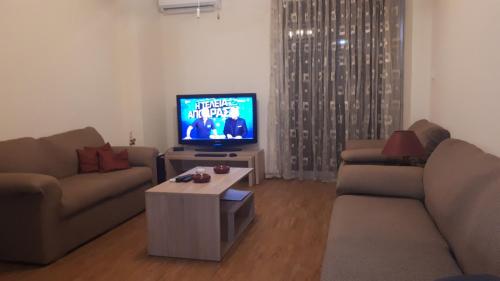 a living room with two couches and a flat screen tv at Alianthos Beach Apartment in Vari