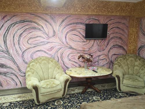 2 Stühle und ein Tisch mit einem TV an der Wand in der Unterkunft Golden Rose in Chişinău