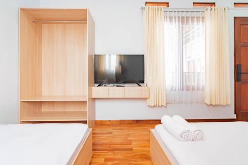 a bedroom with two beds and a tv and a window at Urbanview Hotel One Family Maribaya by RedDoorz in Lembang
