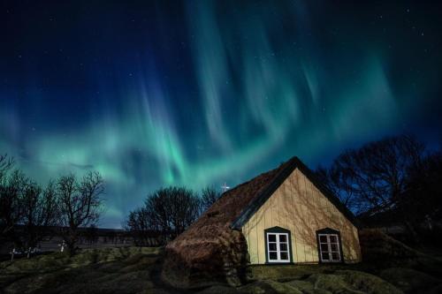 an old barn with the aurora in the sky at Adventure Hotel Hof in Hof