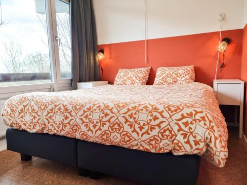 um quarto com uma cama grande e uma parede laranja em Vakantie appartement Chava WE09 em Westkapelle