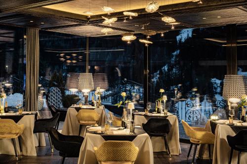 ein Restaurant mit weißen Tischen und Stühlen und einem großen Fenster in der Unterkunft Alpin Garden Luxury Maison & SPA - Adults Only in St. Ulrich in Gröden