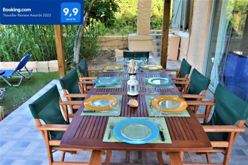 una mesa de madera con platos azules y naranjas. en Private Beach House Irene Mare en Poros