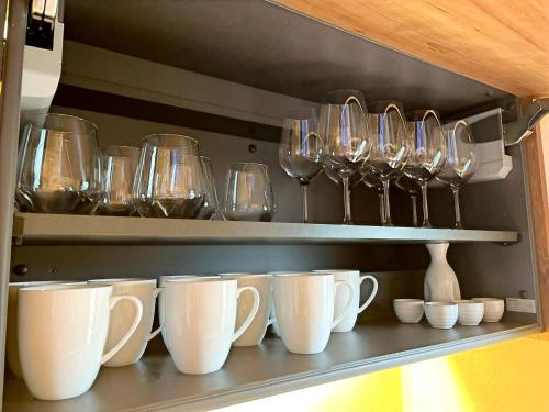 a shelf with cups and wine glasses on it at 弓ヶ浜海水浴場徒歩1分! 一棟貸別荘! Yumigahama Beach House & BBQ! in Minamiizu