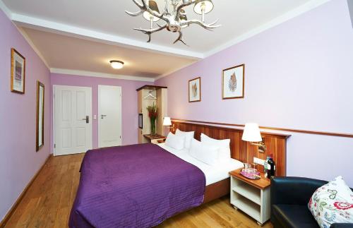 a hotel room with a purple bed and a couch at Hotel Elch in Nuremberg