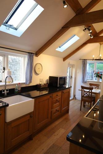 a kitchen with skylights and a kitchen with a sink at Thatched Cottage, beautiful village near the sea in Otterton