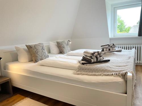 ein großes weißes Bett in einem Zimmer mit Fenster in der Unterkunft Wiesensicht in Archsum