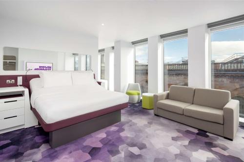 a bedroom with a bed and a couch and windows at YOTEL Glasgow in Glasgow