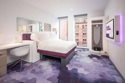 a bedroom with a bed and a desk and a mirror at YOTEL Glasgow in Glasgow