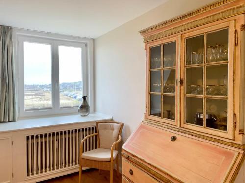 a kitchen with a wooden cabinet and a chair and a window at Norderhof Kliffsand 15 in Kampen