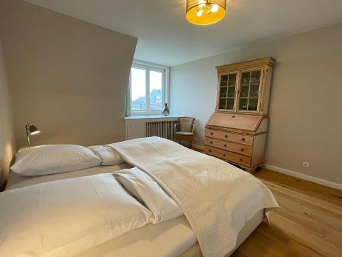 a bedroom with a large white bed and a dresser at Norderhof Kliffsand 15 in Kampen