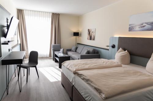 ein Hotelzimmer mit einem Bett und einer Couch in der Unterkunft TIDE Hotel in Wilhelmshaven
