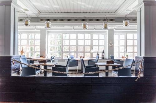 a large room with tables and blue chairs and windows at TIDE Hotel in Wilhelmshaven