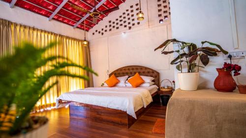 a bedroom with a bed with orange pillows and a plant at Saveda Farm & Cottages in Karjat