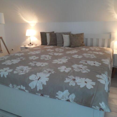 a bedroom with a bed with a floral bedspread at Levendulas Apartman in Balatonalmádi