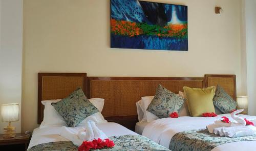 two beds in a hotel room with flowers on them at Mountain View Hotel in La Digue