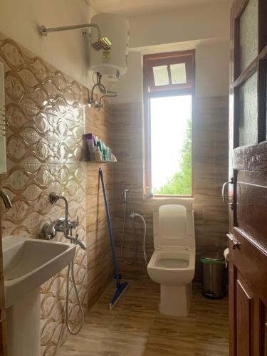 baño con aseo y lavabo y ventana en The Himalayan Workation en Darjeeling