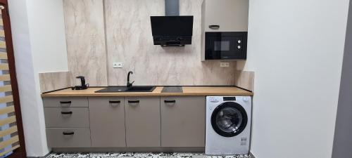 a kitchen with a sink and a washing machine at Centrum Apartman LEYLA I in Bardejov