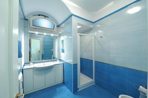 Baño azul con lavabo y espejo en Dolce Vita B, en Amalfi