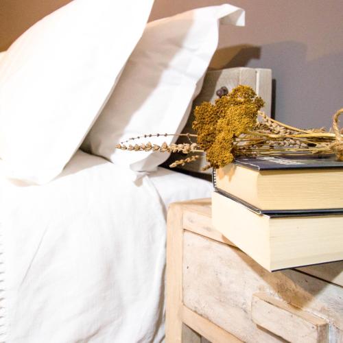 a pile of books on a night stand next to a bed at Ca Veja B&B Forlì in Forlì