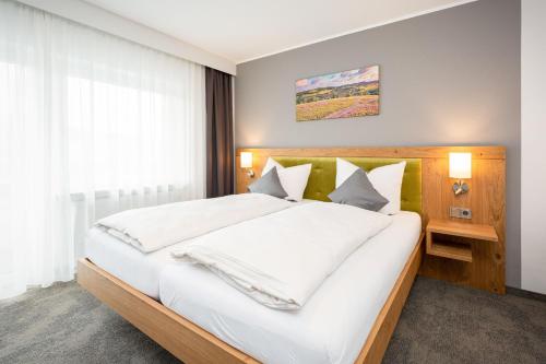 a bedroom with a large bed with white sheets and pillows at Die Landpension FernW in Willingen