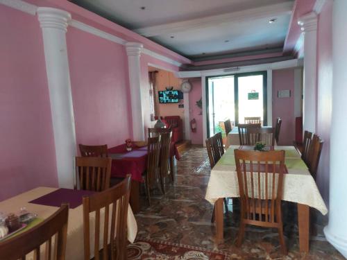 a dining room with tables and chairs and pink walls at SkylineInn Hotel in Surinam