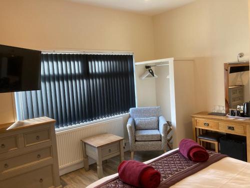 a bedroom with a bed and a chair and a window at The Quies in Newquay
