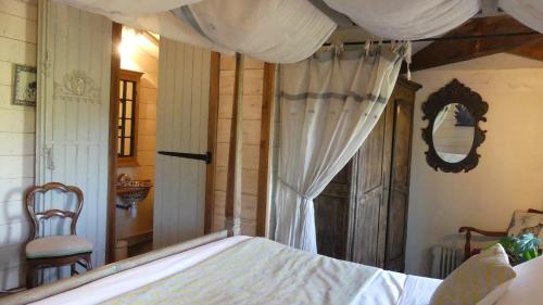 a bedroom with a bed with a canopy and a chair at Domaine de l’Escuderia in Parentis-en-Born