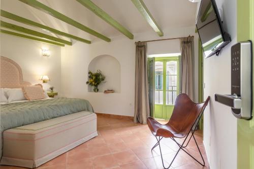 sypialnia z łóżkiem, krzesłem i telewizorem w obiekcie La Abadia de Giralda w Sewilli