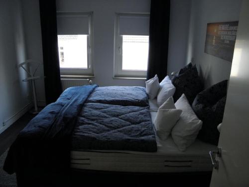 a bedroom with a bed with a blue blanket and two windows at Altstadtwohnung in Verden