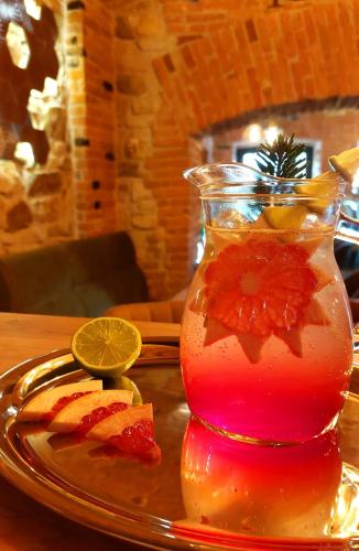 a drink in a vase on a plate with fruit at Hotel Buchenland in Gura Humorului