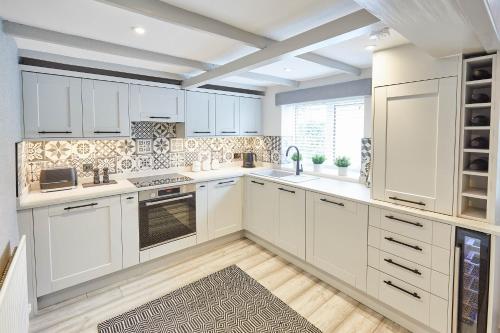 a kitchen with white cabinets and a large window at Host & Stay - 19 West End in Hurworth