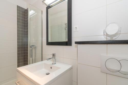 La salle de bains blanche est pourvue d'un lavabo et d'un miroir. dans l'établissement Rony studio, à Split