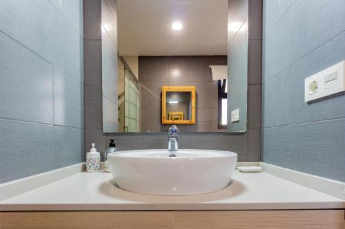 W łazience znajduje się biała umywalka i lustro. w obiekcie RentalSevilla De paseo por los Remedios w Sewilli