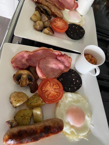 Dos platos de desayuno con huevos, salchichas y tomates. en Westergate House, en York