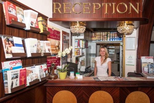 Una donna in piedi dietro un bancone in una libreria. di Pension Neuer Markt a Vienna