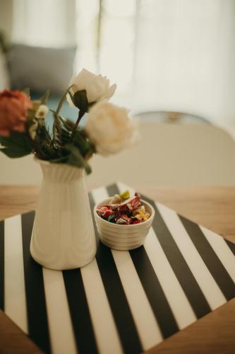 a white vase with a bowl of flowers on a table at Apartman Bombonica in Banja Koviljača