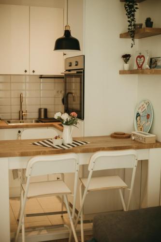 a kitchen with a counter with two stools and a table with flowers at Apartman Bombonica in Banja Koviljača
