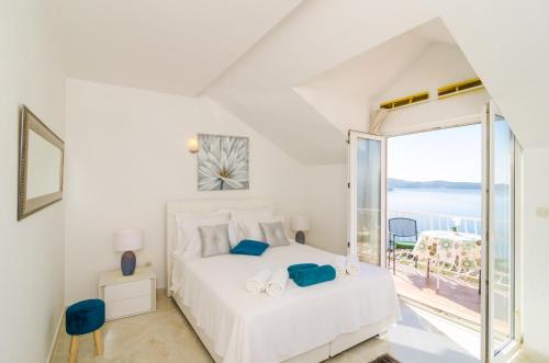 a white bedroom with a bed and a large window at Apartments Sandito in Mlini