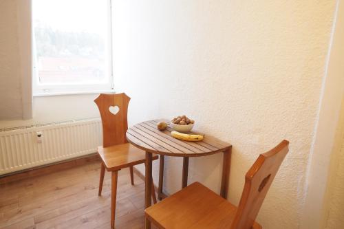 a small table and chairs with a bowl of fruit on it at Haus Felsenpost in Stadt Wehlen