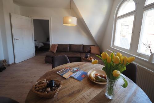 a living room with a wooden table with a vase of flowers at Haus Felsenpost in Stadt Wehlen
