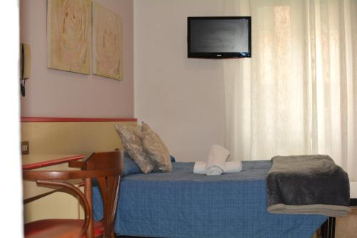 a bedroom with a bed with a tv on the wall at HOTEL LA MADUNINA in Varazze